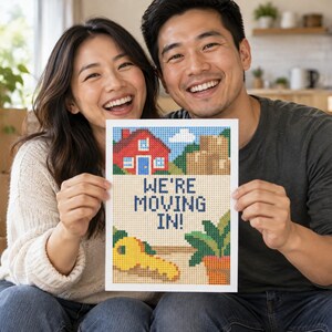 Puede incluir: Una impresi&oacute;n rectangular con un dise&ntilde;o de arte pixelado que muestra una casa roja, cajas de cart&oacute;n marrones, una llave amarilla y una planta verde en maceta. El centro muestra el texto azul oscuro "WE'RE MOVING IN!" sobre fondo claro.