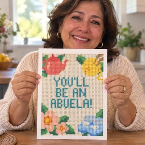 May include: A rectangular craft project featuring a grid pattern with the text YOU'LL BE AN ABUELA! in blue. The design includes a red teapot, a yellow lemon, and pink and blue flowers, all composed of small square tiles on a light background.