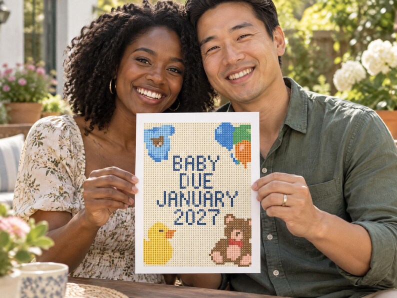 May include: A rectangular white sign featuring a pixelated cross-stitch design with the text BABY DUE JANUARY 2027 in dark blue. The design includes a blue onesie, a cluster of colorful balloons, a yellow rubber duck, and a brown teddy bear.