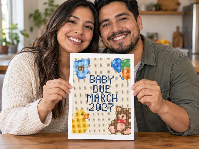 May include: A rectangular white sign featuring a pixelated design with the text BABY DUE MARCH 2027 in dark blue. The design includes a blue baby onesie, a cluster of blue, green, and orange balloons, a yellow rubber duck, and a brown teddy bear.