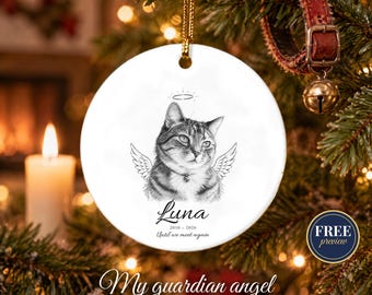 May include: A round white ceramic ornament featuring a black and white sketch of a cat with angel wings and a halo. The text reads Luna, 2010-2026, and Until we meet again. The ornament hangs from a gold cord and is designed for display.