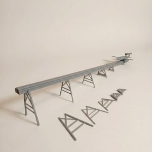 May include: A gray model of a conveyor belt system, with a long, rectangular belt supported by angled supports. Several additional supports are arranged below the belt. The model is designed for architectural or engineering projects.