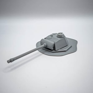 Peut inclure: Un modèle de char gris avec un long canon et une tourelle détaillée. Le char repose sur une base grise et irrégulière. L'image est prise sur un fond blanc.
