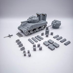 Op de afbeelding: Een grijs model van een tank met een lange loop en diverse componenten, waaronder een aparte toren, vaten en dozen. De tank heeft gedetailleerde tracks en staat tegen een witte achtergrond. Het model is waarschijnlijk voor hobbyisten of verzamelaars.