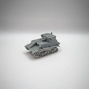 May include: A gray toy tank with a detailed design, featuring a turret, tracks, and small wheels. The miniature tank is a model of a military vehicle, likely for collectors or hobbyists. The tank is made of a solid material and sits on a white surface.