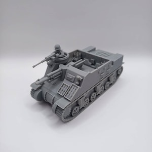 Puede incluir: Maqueta gris de un tanque militar con una figura de soldado en la torreta. El tanque tiene un cañón y múltiples ruedas a cada lado. El modelo está hecho de un material gris sólido y se encuentra sobre una superficie blanca.