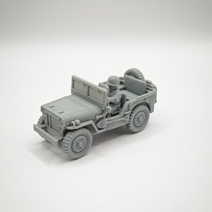 Peut inclure: Un modèle réduit de jeep grise avec une figurine de soldat au volant. La jeep a une roue de secours montée à l'arrière et des roues détaillées. Le véhicule est une réplique miniature d'une jeep militaire.
