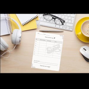May include: A dance practice log with the text "Dance practice log" and the quote "Small steps lead to big lifts" sits on a wooden desk. Other items include a keyboard, headphones, a cup of coffee, and a notebook.