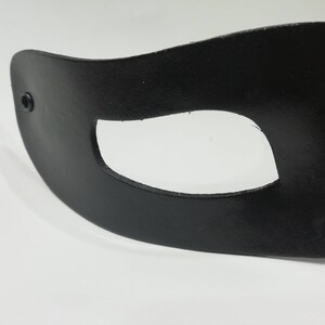 Puede incluir: M&aacute;scara para los ojos de cuero negro con un solo agujero para el ojo. La m&aacute;scara tiene un peque&ntilde;o remache negro en el lateral.