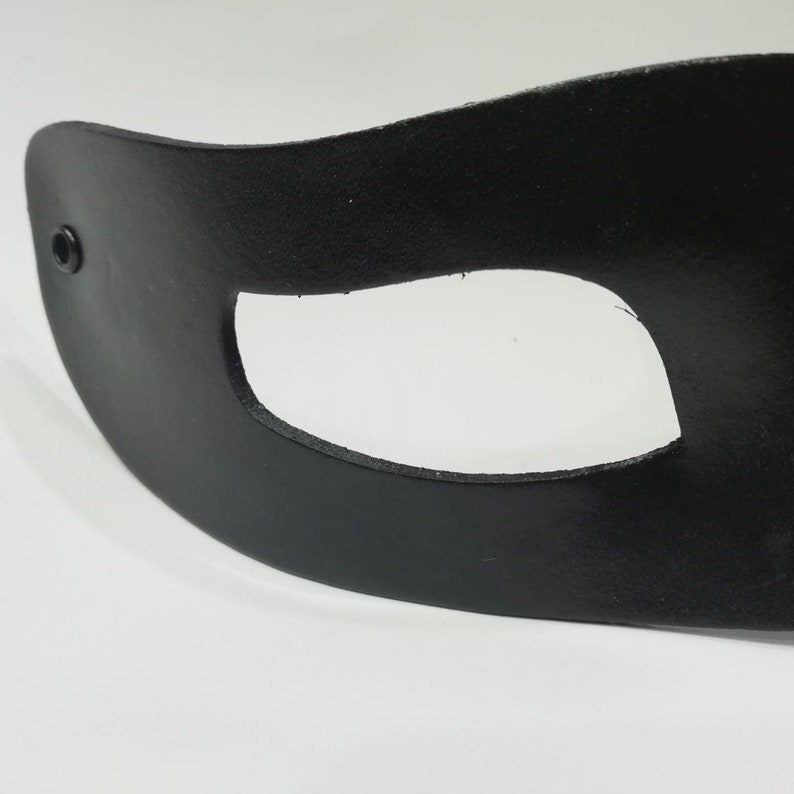 Puede incluir: M&aacute;scara para los ojos de cuero negro con un solo agujero para el ojo. La m&aacute;scara tiene un peque&ntilde;o remache negro en el lateral.