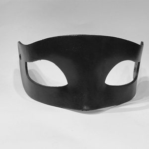 Puede incluir: Una m&aacute;scara para los ojos de cuero negro con dos agujeros para los ojos. La m&aacute;scara es curva y tiene un dise&ntilde;o simple.