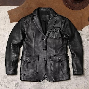 Puede incluir: Un blazer de cuero negro con un diseño clásico. La chaqueta presenta solapas con muescas, tres botones y cuatro bolsillos delanteros. El blazer es de peso medio y parece estar hecho de cuero genuino.
