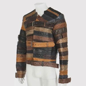 Puede incluir: Chaqueta de cuero patchwork en tonos marr&oacute;n, negro y beige. La chaqueta presenta tiras horizontales de cuero, aseguradas con m&uacute;ltiples cierres de hebilla. Las mangas tienen detalles de hebilla en los pu&ntilde;os. La chaqueta se exhibe en un maniqu&iacute;.