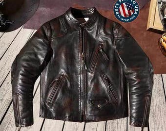 May include: A dark brown leather jacket featuring a stand-up collar, a central front zipper, and multiple zippered pockets on the chest and sides. The sleeves include zippered cuffs, and the leather has a distressed finish with visible tonal variations.