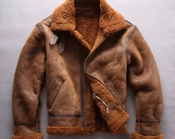 May include: Brown leather jacket with a shearling collar and lining. The jacket features a zipper closure, a buckled strap at the collar, and shearling trim at the cuffs and hem. The jacket has a vintage, worn look.