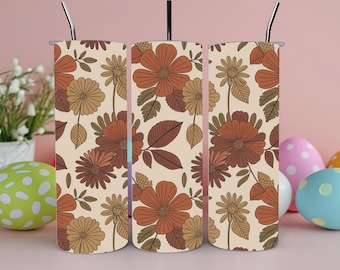 May include: A set of three floral-patterned insulated tumblers with stainless steel straws. The design features large orange, brown, and tan flowers and leaves on a cream background. Easter eggs in various colors are in the background.