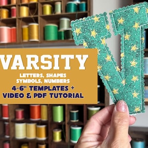 May include: A green fabric letter V with a yellow star pattern and scalloped edges. A gold overlay features the text: VARSITY LETTERS, SHAPES SYMBOLS, NUMBERS 10-15 cm TEMPLATES + VIDEO & PDF TUTORIAL. The letter is held against a background of thread spools.