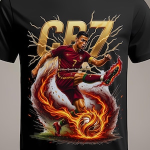May include: Black t-shirt featuring a dynamic illustration of a soccer player in a red and gold uniform kicking a flaming soccer ball. The design includes the text "CR7" in gold, with lightning bolt accents.
