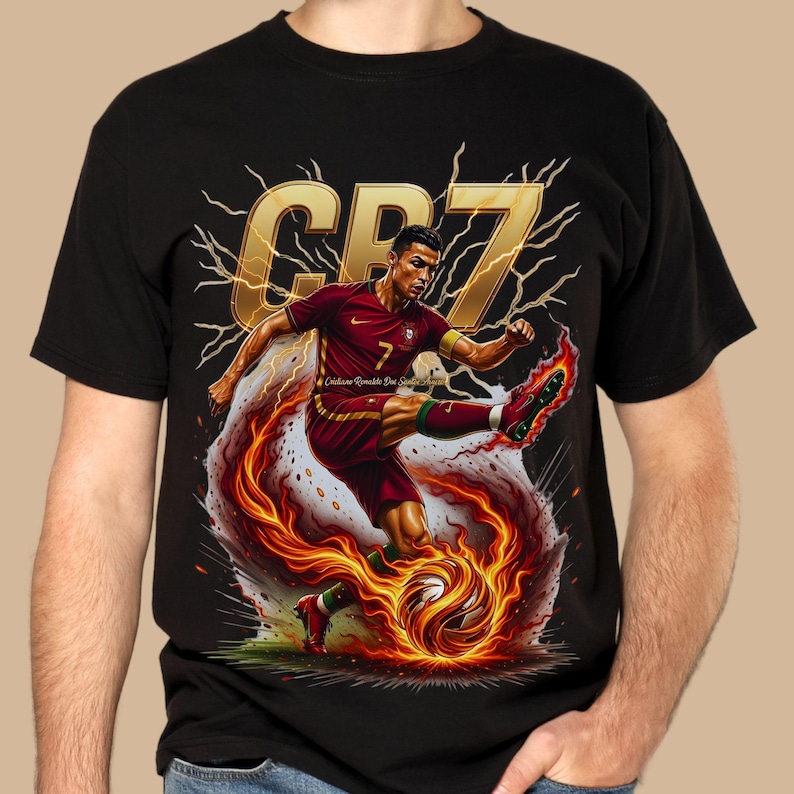 May include: Black t-shirt featuring a dynamic graphic of a soccer player in a red and green uniform kicking a flaming soccer ball. The design includes the text "CR7" in gold, with lightning bolt accents.