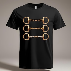 May include: A black short-sleeve t-shirt featuring a graphic print of three horizontal gold-colored horse bits stacked vertically. The top bit has a black and gold diamond pattern, the middle has a leopard print, and the bottom has a dalmatian print.