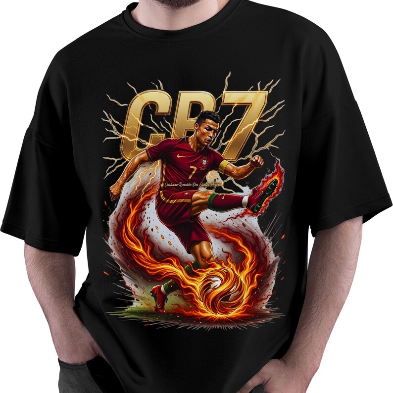 May include: Black t-shirt featuring a dynamic illustration of a soccer player in a maroon uniform kicking a flaming soccer ball. The design includes the gold letters "CR7" and lightning bolt accents.
