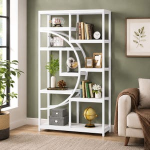 May include: A tall white bookshelf featuring a geometric design with a large circular frame integrated into the rectangular structure. The shelves hold various decorative items including books, a globe, a small ship in a bottle, and storage boxes.