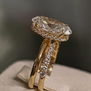May include: A gold ring featuring a large marquise-cut centre stone surrounded by a halo of small round diamonds. The band is also adorned with a row of small round diamonds along the side, showcasing a polished gold finish and intricate metalwork.