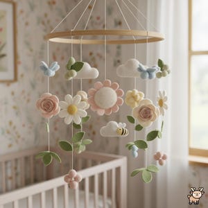 Peut inclure: Un mobile de chambre d'enfant composé d'un cadre circulaire en bois avec des éléments en feutrine suspendus, incluant des fleurs roses et blanches, des feuilles vertes, des nuages blancs, des papillons bleu clair et une abeille jaune et noire.