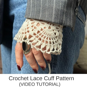May include: Cream-colored crochet lace cuff with a scalloped edge, worn with a gray pinstripe blazer and blue jeans. The cuff features an openwork design. The text at the bottom reads "Crochet Lace Cuff Pattern (VIDEO TUTORIAL)".