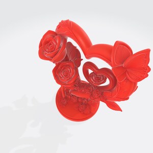 May include: A vibrant red decorative sculpture featuring a heart-shaped design, adorned with roses, a butterfly, and smaller heart accents. The sculpture is set on a round base, showcasing intricate details and a smooth finish.