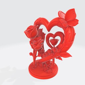 May include: A red decorative sculpture featuring a heart-shaped frame with a butterfly and roses. The sculpture has a round base and includes a smaller heart with a rose in the center. The roses are intricately detailed.