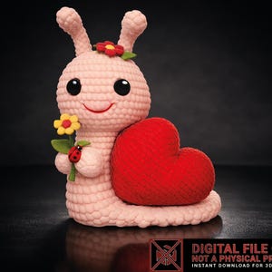 May include: A crocheted snail figurine with a red heart-shaped shell. The snail is light pink with large black eyes, a smiling mouth, and a flower on its head. It holds a flower and a ladybug. The image includes the text "DIGITAL FILE ONLY".
