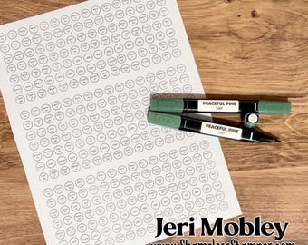 Può includere: Un foglio di carta bianco stampato con una griglia di piccoli cerchi contenenti vari nomi di colori e numeri, accompagnato da due pennarelli a doppia punta in tonalità di verde etichettati Peaceful Pine Dark e Peaceful Pine Light.