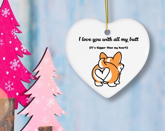 May include: A white heart-shaped ornament with the text "I love you with all my butt (it's bigger than my heart)" and a cartoon corgi butt illustration. The ornament hangs from a gold string. Pink and magenta Christmas trees are in the background.