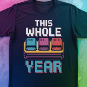 Puede incluir: Camiseta azul marino oscuro con un diseño gráfico. El diseño presenta las palabras "THIS WHOLE YEAR" en letras blancas, con teclas de teclado pixeladas etiquetadas como "CTRL", "ALT" y "DELETE".