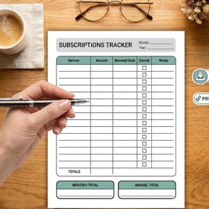 May include: A white subscriptions tracker with a teal header and footer, and a grid for tracking services, amounts, renewal dates, and notes. A hand holds a pen over the tracker. A cup of coffee, glasses, and a small floral arrangement are also visible.