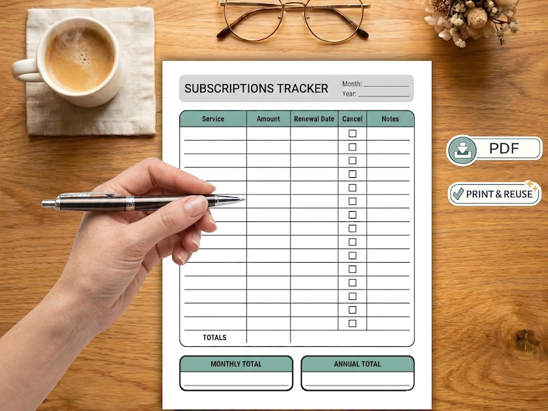 May include: A white subscriptions tracker with a teal header and footer, and a grid for tracking services, amounts, renewal dates, and notes. A hand holds a pen over the tracker. A cup of coffee, glasses, and a small floral arrangement are also visible.