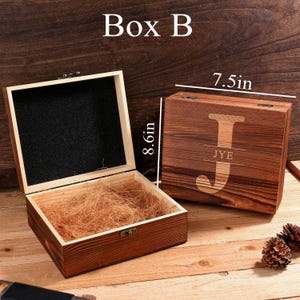 May include: Wooden box with a hinged lid, open to reveal a black interior and straw. The closed box has a large letter "J" engraved on the lid, with "JYE" below. The box is 8.6 inches tall and 7.5 inches wide. The text "Box B" is at the top.
