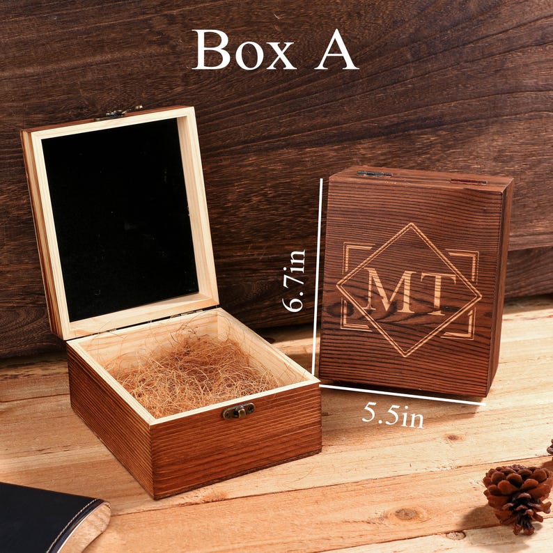 May include: Wooden box with a hinged lid, open to reveal a black interior and straw-like filler. A closed box with the initials "MT" is next to it. The text "Box A" is at the top. The box is 6.7 inches tall and 5.5 inches wide.