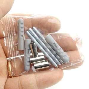 May include: A clear plastic bag containing various hardware items. The contents include several silver screws, gray plastic wall anchors, and silver metal clips. The items are held in a person's hand.
