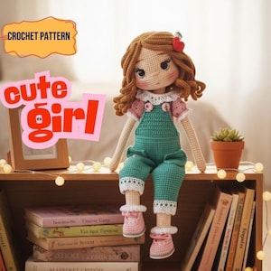 Peut inclure: Poupée au crochet faite à la main, avec des cheveux bruns bouclés, vêtue d'une salopette verte, d'une chemise rose et de chaussures roses. La poupée a un accessoire en forme de cœur rouge dans les cheveux. Le texte sur l'image indique "CROCHET PATTERN" et "cute girl".