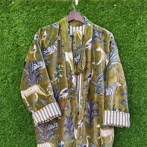 Op de afbeelding: Olijfgroene fluwelen kimono met een dierenprint uit de jungle. Het ontwerp bevat zebra's, luipaarden, vogels en palmbomen. Het heeft gestreepte manchetten en een bijpassende ceintuur.