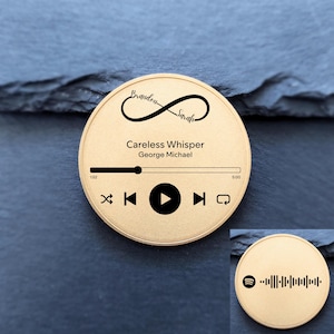May include: A gold-colored round keepsake with a music player interface design. The design includes the song title "Careless Whisper" by George Michael, with the names "Brandon" and "Sarah" above an infinity symbol. A smaller disc with a Spotify code is also visible.