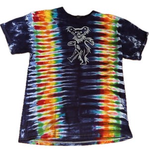 May include: A tie-dye t-shirt with a dancing bear graphic. The shirt features a vibrant rainbow pattern across the chest and a dark blue tie-dye pattern on the sleeves and shoulders. The bear graphic is in a silver color.