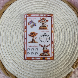 Puede incluir: Una hoja de pegatinas rectangular con ilustraciones de temática otoñal que incluyen un ternero, una calabaza, un burro y bellotas. El texto dice "Kras & Spaar", "Kleur & Spaar" y "Dobbel en Spaar". El diseño incluye elementos circulares holográficos.