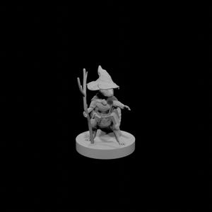 Peut inclure: Miniature grise imprimée en 3D d'un personnage fantastique, une créature ressemblant à une tortue portant un chapeau de sorcier et tenant un bâton. La figurine est sur une base circulaire, avec un design détaillé. Le fond est noir.