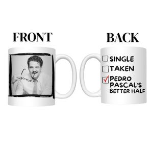 May include: A white ceramic mug with a black and white image of a man on the front. The back of the mug has a checklist with "Pedro Pascal's Better Half" checked. The mug has a white handle.