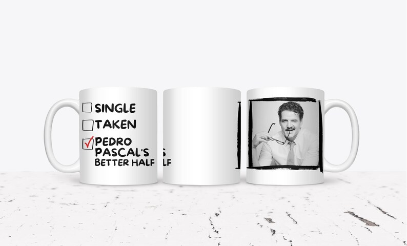 May include: White ceramic mug with a black and white image of a man holding glasses. The mug has the text "SINGLE", "TAKEN", and "PEDRO PASCAL'S BETTER HALF" with a checkmark next to the last option.