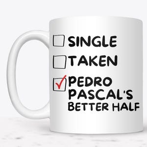 May include: White ceramic mug with the text "SINGLE", "TAKEN", and "PEDRO PASCAL'S BETTER HALF". The "PEDRO PASCAL'S BETTER HALF" option is checked with a red checkmark. The mug has a white handle.