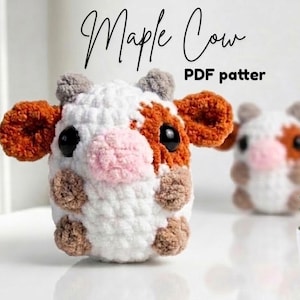 Könnte beinhalten: Gehäkelte Kuh mit weißen, braunen und orangefarbenen Details. Die Kuh hat große schwarze Augen, eine rosa Nase und braune Hufe. Der Text "Maple Cow PDF pattern" steht in schwarzer Schrift über der Kuh.